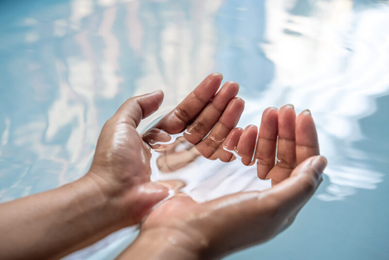 Female hands cupped together partially submerged in clear blue w